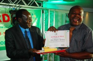 Dr Wilbur Ottichilo, environment scientist and a Kenya Member of Parliament hands over a certificate and other prizes to Elias Ntungwe (right) during a gala night in Nairobi.