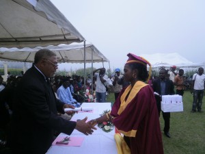 Rep of Buea Mayor (L) congratulates a hard working graduate with a prize