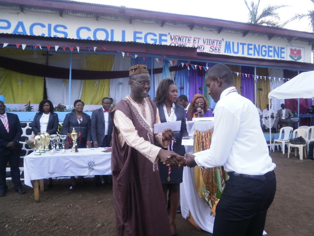 Gabriel Njikang(L) Representative of the Delegate of Secondary Education hands a prize to a student
