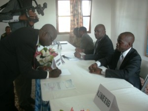 Markus Motove(L) a beneficiary, signs out his cheque, while CAMWATER and administrative officials look on