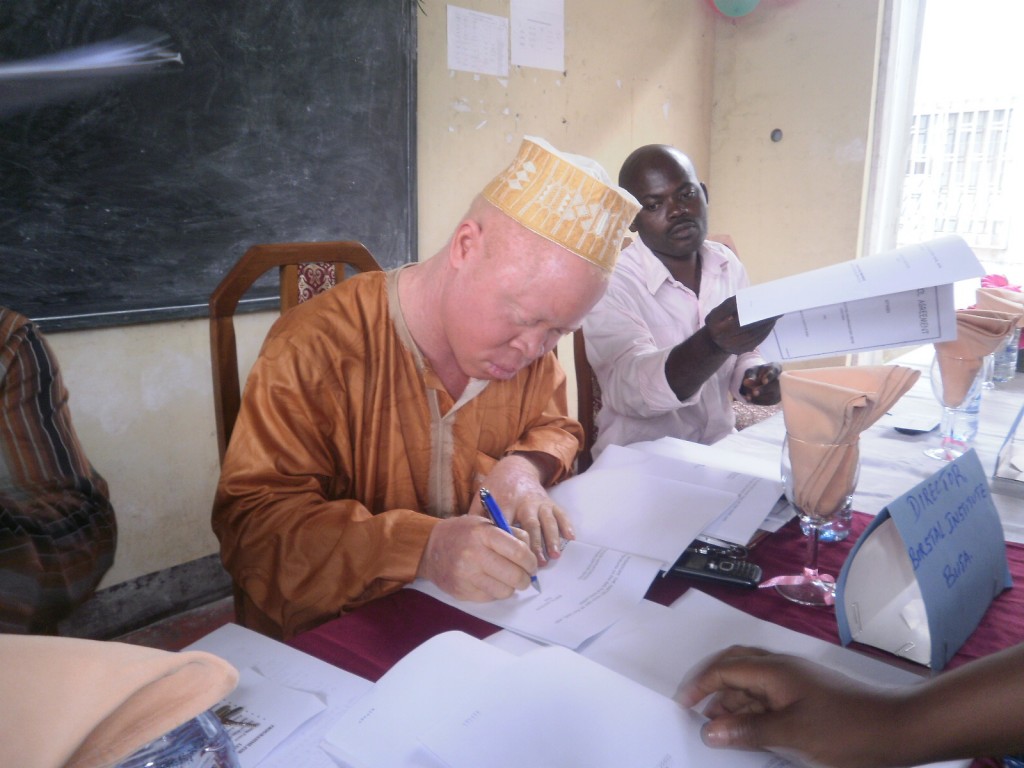 Fidelis Njie Ewumbue, Director, Borstal Institute, putting pen on paper at the MOU ceremony