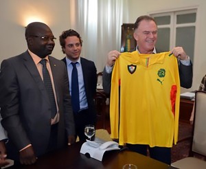 HE Jose Casagrande, Governor of Espiriti Santo state(R) brandishes a jersey of the Indomitable Lions offered to him by the SG of FECAFOOT(L)