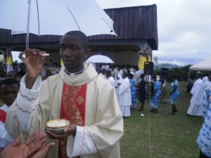 One of the newly ordained Priests, Rev.Fr Herbert Niba offers Communion at the Ordination Mass